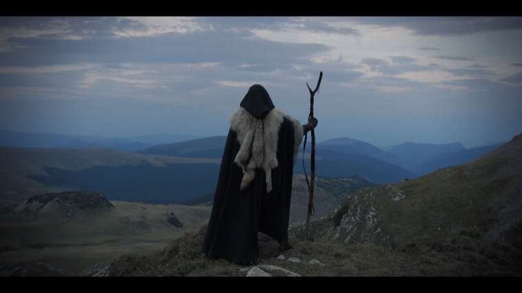 Merlin (Tom Sharp) above the valley, opening the story he calls Arthur’s: “I am the man who made him.”
